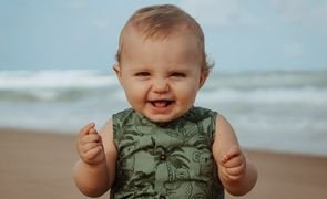 Menino sorrindo com água do mar ao fundo