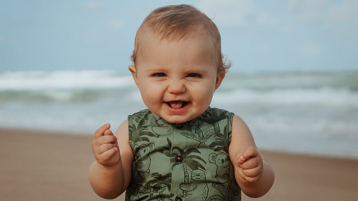 Menino sorrindo com água do mar ao fundo